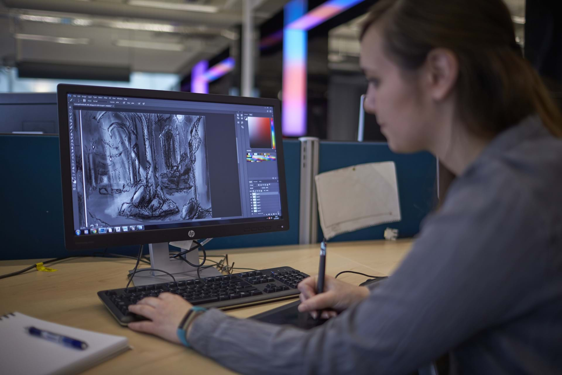 The image shows a female gaming student working at a computer creating a video game.