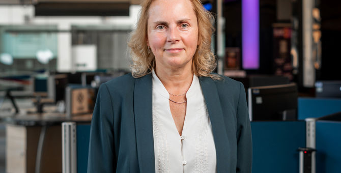 A portrait of principal Liz Bacon, a woman with blonde hair wearing a blue blazer and white blouse.